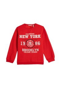 Czerwona bluza z długim rękawem z białym napisem "Champions New York 1986 Brooklyn College League" oraz okrągłym emblematem Nowego Jorku.