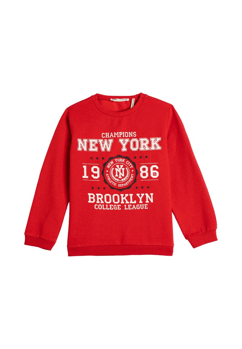 Czerwona bluza z długim rękawem z białym napisem "Champions New York 1986 Brooklyn College League" oraz okrągłym emblematem Nowego Jorku.
