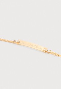 Kuldne käevõru, millel on graveering "Lauren Ralph Lauren" vardal, ühendatud ahelaga, mille mõlemal otsal on väikesed sissepandud läbipaistvad kivid.