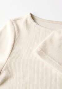 Maglione texture beige chiaro con scollo rotondo e maniche lunghe, caratterizzato da un motivo a costine e un tessuto morbido.