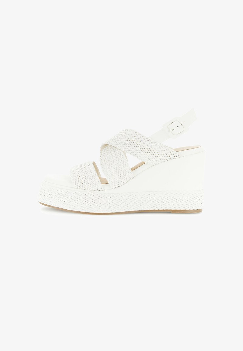 Sandalia blanca de cuña con tiras entrelazadas y hebilla ajustable en el tobillo, con suela de plataforma texturizada.