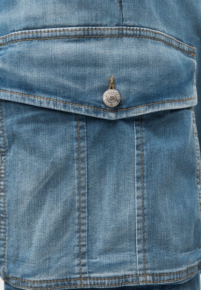 Τσέπη τζιν μπουφάν με καπάκι ασφαλισμένο με μεταλλικό κουμπί χαραγμένο "Square since 1995", εμφανής ραφή σε νήμα καφέ αποχρώσεων.