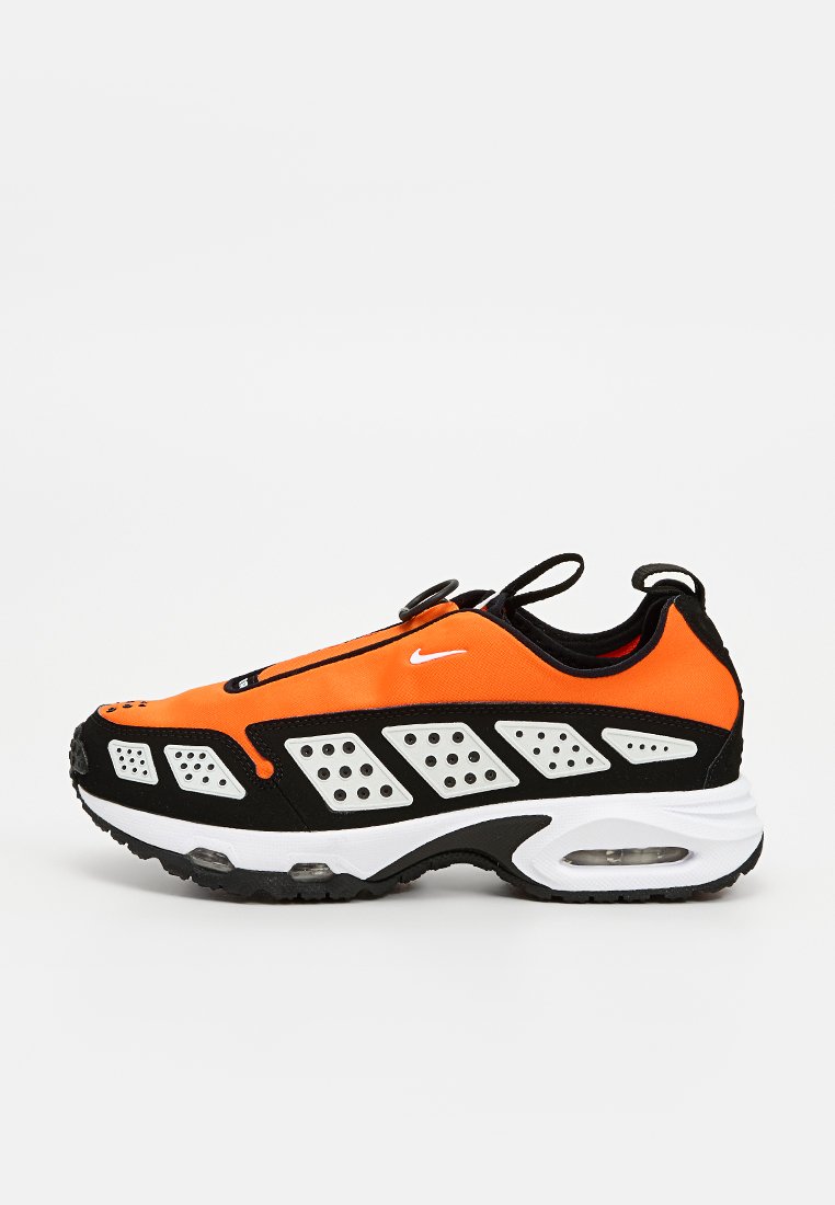 Zapatilla Nike con una parte superior naranja y detalles en negro, media suela blanca y perforaciones para la transpirabilidad. Tejido liso y forma redondeada.