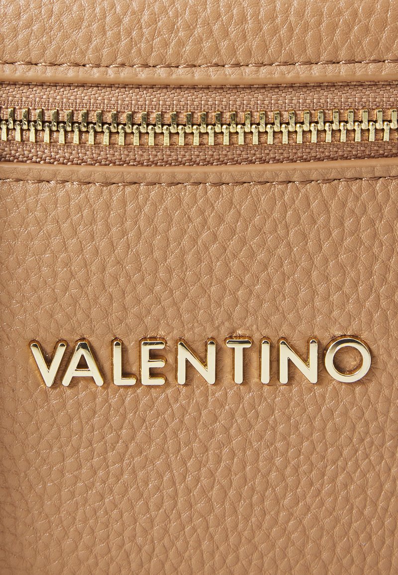 Bolso de mano de cuero marrón claro con una textura suave, cierre dorado y logo grabado "VALENTINO" en letras mayúsculas.