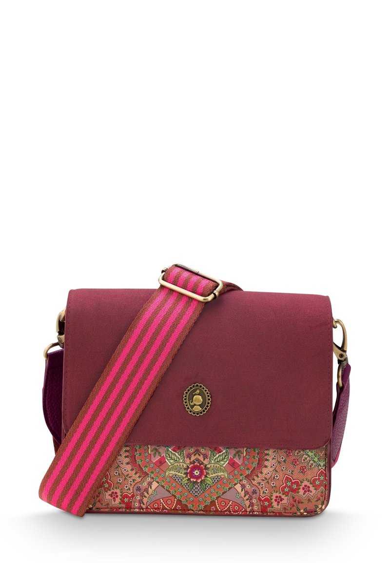 Bordeaux crossbody tas met een gemusterde onderpaneel. Voorzien van een gestreepte roze schouderriem en een ronde decoratieve embleem op de klep.