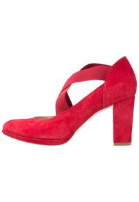 Chaussure à talon haut en daim rouge avec un bout arrondi et des sangles élastiques croisées sur le dessus. Talon carré pour plus de stabilité.