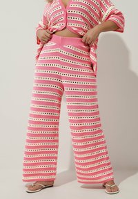 Szydełkowane różowo-białe paskowane spodnie w szerokim kroju z wycięciami, z grubym elastycznym paskiem w talii.