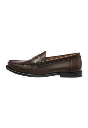 Ruskea nahkainen slip-on-mokkasiini, jossa matala musta pohja, pyöreä kärki ja hillitty ompelukoristelu edessä ja sivuilla.