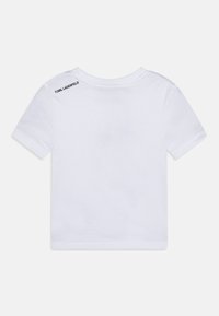 Balts kokvilnas T-krekls, īsām piedurknēm, apaļa kakla izgriezuma. Aizmugurē pie kakla ir melns teksts "KARL LAGERFELD". Gluda tekstūra.