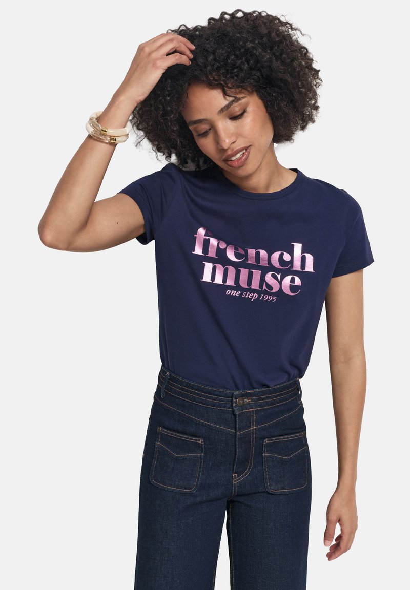 Camiseta de manga corta color azul marino con un gráfico impreso en rosa que dice "musa francesa" y "un paso 1995" en el frente. Material de algodón.