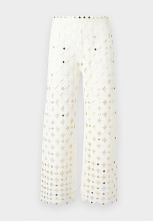 Pantalon blanc à jambes larges avec motif en dentelle florale et petits clous réfléchissants uniformément disposés sur tout le tissu.