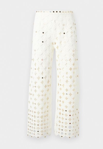 Pantalon blanc à jambes larges avec motif en dentelle florale et petits clous réfléchissants uniformément disposés sur tout le tissu.