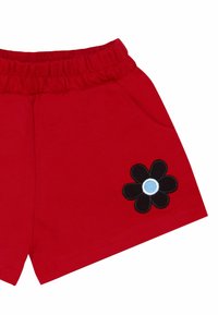Pantalones cortos de algodón rojos con cintura elástica, que cuentan con bolsillos frontales y un bordado de flor negra con un centro azul en el costado.