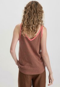Gestreept tanktop in bruin met roze accenten. Heeft een V-hals aan de achterkant en een losse pasvorm, gemaakt van zachte stof.