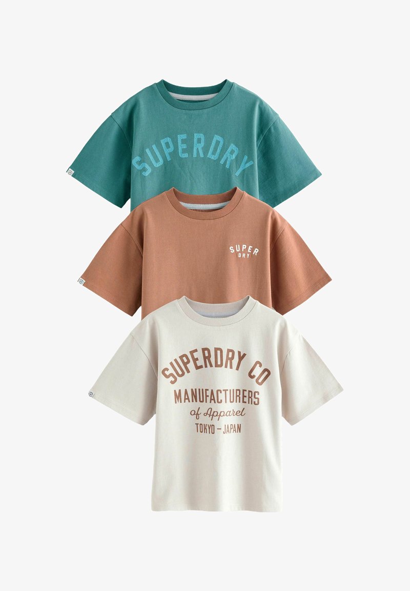 Tre kortærmede t-shirts: grøn med blå tekst, brun med hvid tekst og creme med brun skrift. 100% bomuldsstof, afslappet pasform.