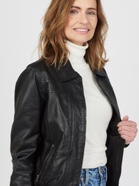Schwarze Lederjacke mit Reißverschluss, ausgestattet mit einem klassischen Kragen und seitlichen Taschen. Getragen über einem weißen Rollkragenpullover und blauen Jeans.
