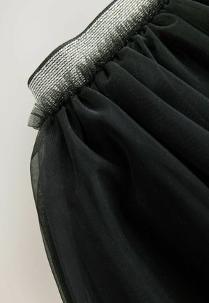 Jupe en tulle noir avec une taille élastique, ornée d'un liseré métallique argenté. Le tissu a une texture douce et légère avec des volants superposés.