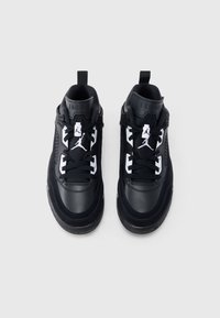 Ζευγάρι ασπρόμαυρων αθλητικών παπουτσιών Air Jordan από ψηλά σε γκρί φόντο, με λογότυπα Jumpman στη γλώσσα τους.