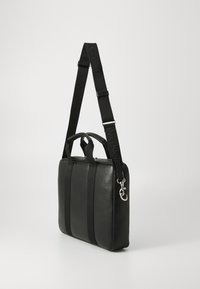 Schwarze Lederhandtasche mit rechteckiger Form, doppelten oberen Griffen und einem verstellbaren Schulterriemen mit einem Logo. Glatte Textur mit Nüancen von Nähten.