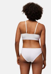 Bralette blanco de algodón con tirantes ajustables y bragas de talle alto a juego. Textura suave, diseño casual y sin patrones visibles.