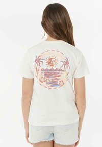 Witte katoenen t-shirt met een kleurrijke zon- en strandafbeelding op de achterkant, met palmbomen en bloemen, korte mouwen en een relaxte pasvorm.