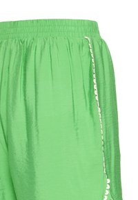 Shorts en satin vert clair avec une ceinture élastique et un bord festonné blanc le long de la couture latérale.