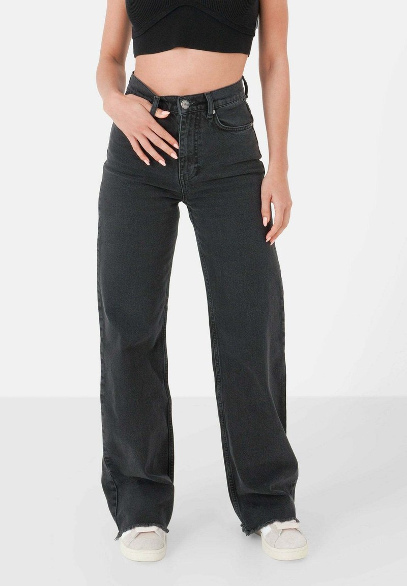 Jeans en denim noir taille haute avec une coupe décontractée, dotés d'une fermeture à boutons, de cinq poches et d'ourlets effilochés à la cheville.