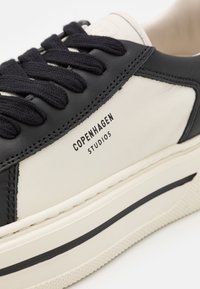 Skórzane sneakersy z granatową cholewką i beżowym panelem bocznym, czarne sznurowadła oraz logo "COPENHAGEN STUDIOS" na boku.