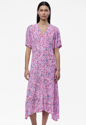 Rosa medellång klänning med blommönster i rött, blått och grönt. Korta ärmar och V-ringning, med en diskret hög-låg fåll.