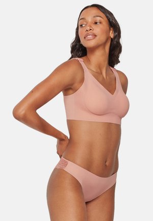 Set di reggiseno e slip coordinati di colore rosa chiaro realizzati in tessuto morbido, con un design a scollo a V e un tocco di pizzo sul lato dello slip.