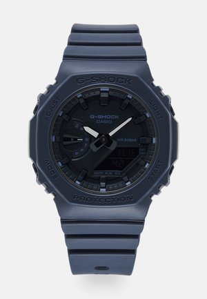 Analog-digital G-SHOCK-Uhr mit einem matten navyblauen Kunststoffgehäuse und -armband. Verfügt über ein schwarzes Zifferblatt mit silbernen Akzenten und mehreren Funktionsknöpfen.