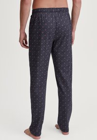 Zwarte pyjamabroek met een geometrisch patroon in roze en wit, voorzien van een elastische tailleband en een ontspannen pasvorm. Gladde stofstructuur.