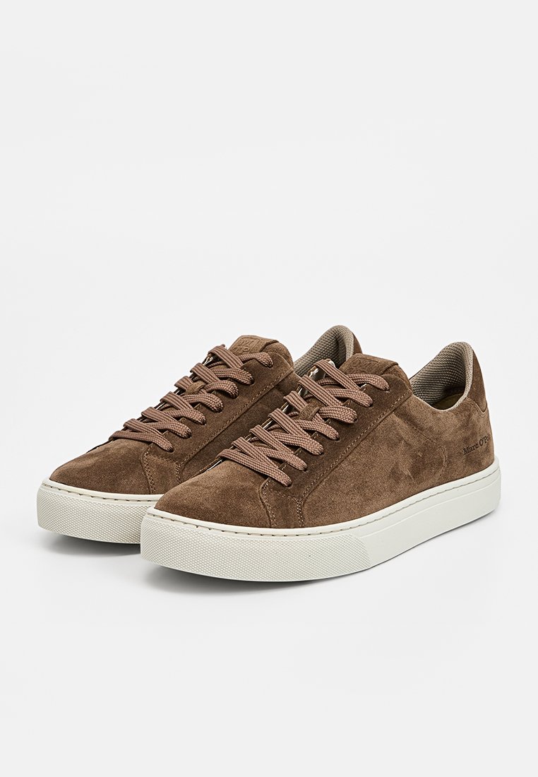 Braune Wildledersneaker mit beigen Gummisohlen, die ein Low-Top-Design und flache Schnürsenkel aufweisen, wobei sie eine glatte Textur und einen minimalistischen Stil präsentieren.