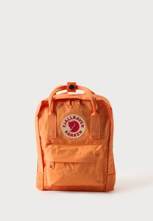 Malý oranžový batoh Fjällräven Kånken s hornými rukoväťami, predným vreckom na zips a okrúhlym logom na jednofarebnom pozadí.