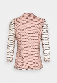 Maglietta a maniche lunghe con corpo rosa e pois neri, anche le maniche sono decorate con pois neri. Texture liscia.