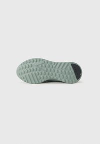 Suela de zapatilla de goma verde con superficie texturizada, patrones de agarre circulares y una etiqueta negra con el nombre de la marca "ARKK."