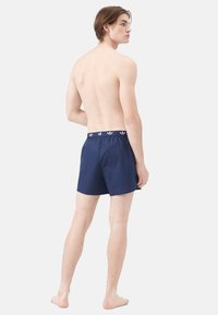 Pantaloni da nuoto blu navy con vita elasticizzata, caratterizzati da dettagli con logo bianco. Realizzati in un materiale leggero, hanno una vestibilità ampia e comoda.