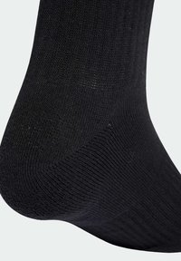 Čierna ponožka z rebrovanej látky, s hladkou textúrou a spevnenou špičkou. Dizajn zahŕňa tesné priliehanie s minimálnymi detailmi.