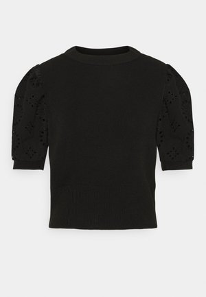 Haut noir en maille à manches courtes avec col rond et manches bouffantes en dentelle ajourée présentant des motifs floraux découpés.