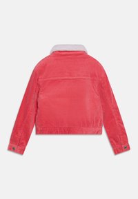 Červená manšestrová bunda s bílým límcem z beránkoviny, krátký střih, dlouhé rukávy a manžety na knoflíky. Viditelná struktura látky.