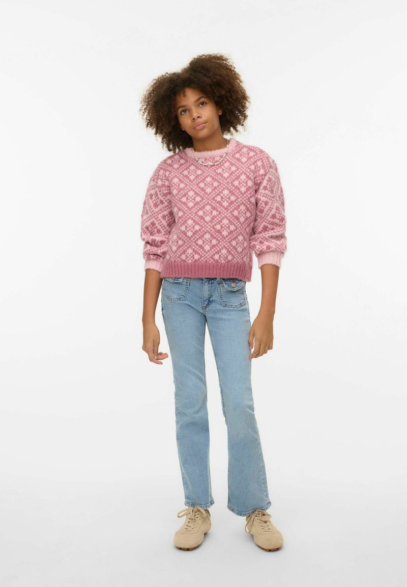 Rozā džemperis ar rakstu un dimanta dizainu, ribotām aprocēm un apakšmalu, saskaņots ar gaiši ziliem džinsiem un bēšām sporta kurpēm. Vienkāršs, ikdienišķs apģērbs.