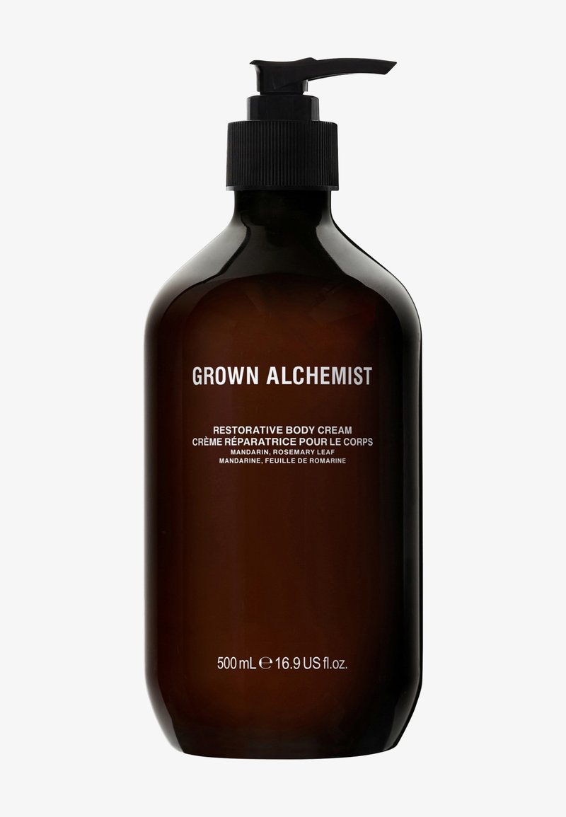 Bruine glazen pompflacon met herstellende bodycrème, voorzien van witte tekst. Bevat 500 ml. Opvallende noten: mandarijn, rozemarijnblad.