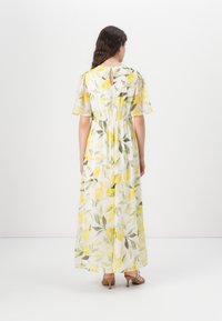 Rochie maxi cu un imprimeu de lămâi și frunze verzi pe un material alb transparent, îngustată la talie, cu mâneci scurte și un detaliu lacăt la spate.