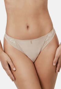 Culotte bikini nude avec bord en dentelle et corps en maille lisse ; présente des motifs floraux délicats sur les côtés et une subtile touche métallique.