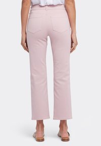 Pantalones de mezclilla rosa claro acampanados con una cintura de media altura, que cuentan con dos bolsillos traseros y una textura suave y ligeramente elástica.
