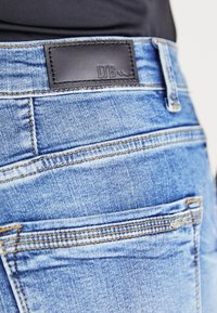 Lichtblauwe denim jeans met een zwart leren label met de tekst "LTB" op de tailleband. Voorzien van klassieke stiksels en een subtiele textuur.