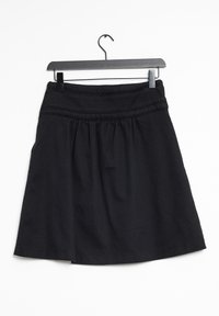 Jupe noire avec un tissu texturé, dotée d'une taille ajustée, d'un design froncé et d'une forme légèrement évasée, suspendue à un crochet noir.