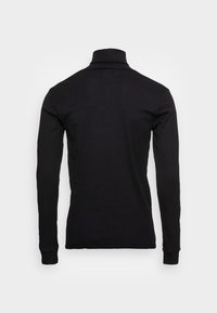 Camisa polo de manga larga negra con cuello alto y puños acanalados, fabricada con un tejido de algodón suave y un diseño ajustado.