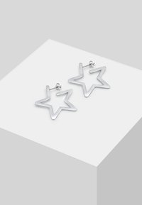 Silver star-shaped earrings with a smooth, minimalistic design. Features open shapes and a stud closure for secure wear.
