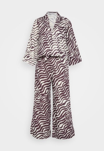 Tvådelad loungedräkt med ett vitt och mörklila vågmönster. Skjortan har krage och knäppning; byxorna är vida med elastisk midja.
